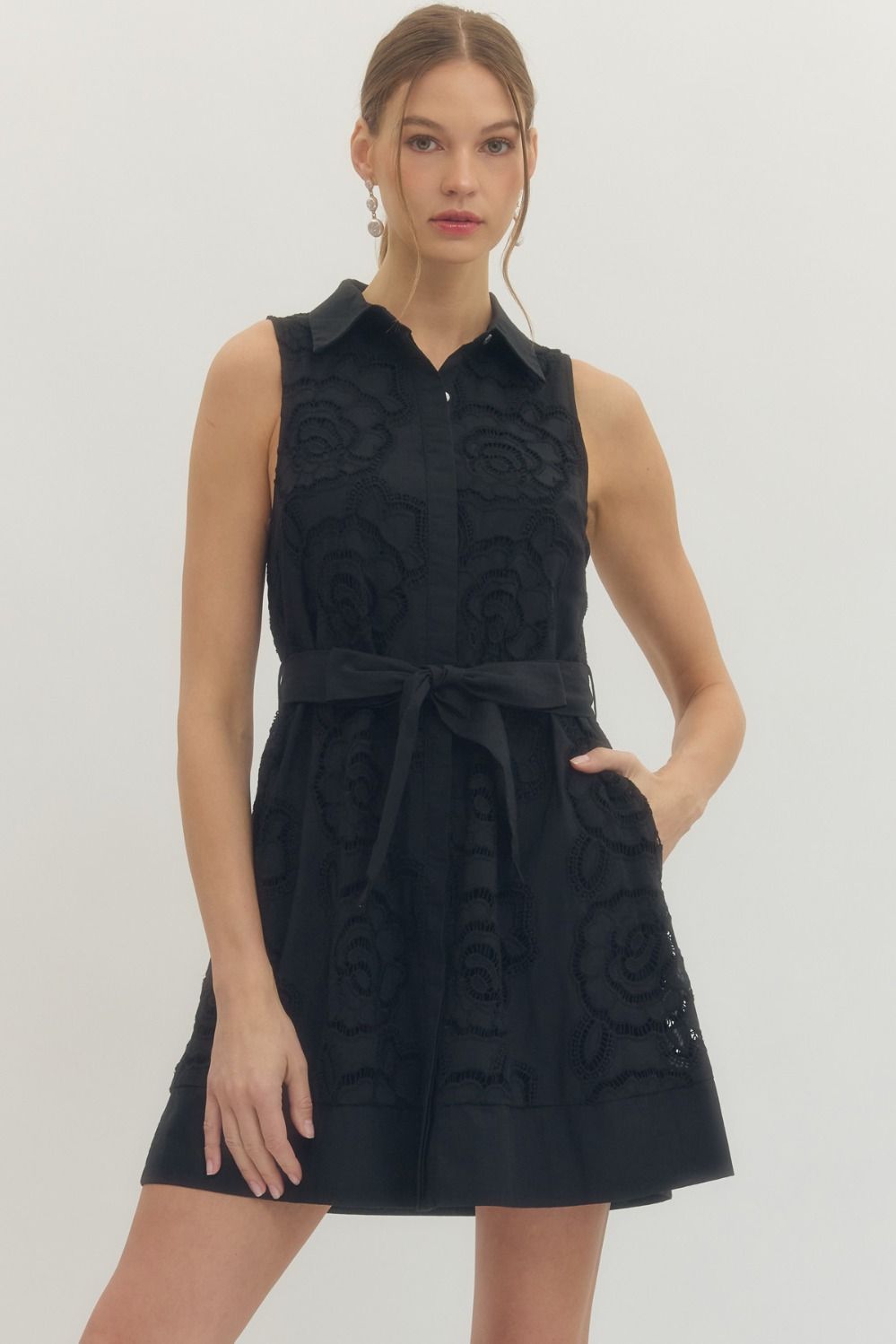Solid sleeveless mini dress featuring floral lace overlay and self-tie belt at waist