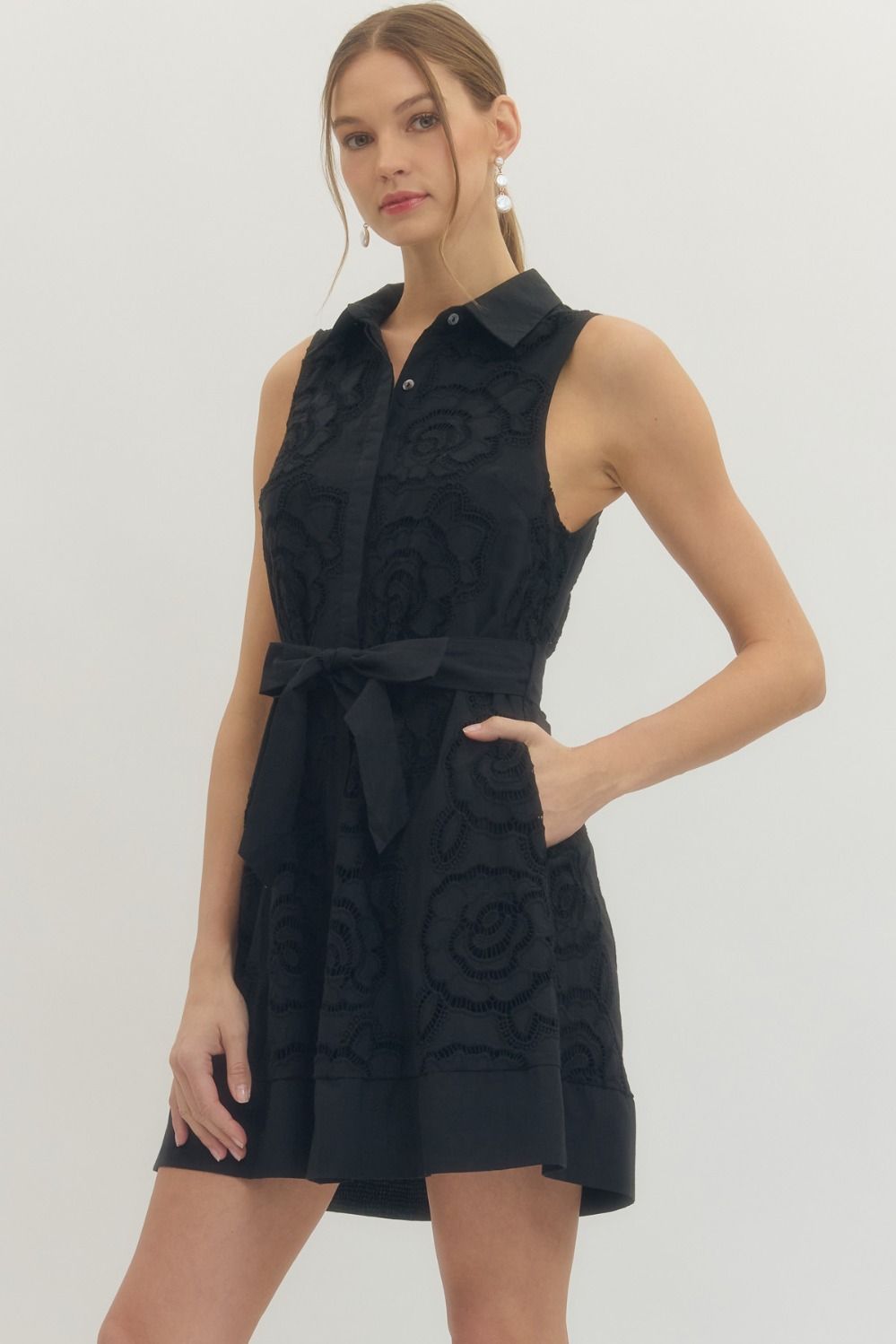 Solid sleeveless mini dress featuring floral lace overlay and self-tie belt at waist
