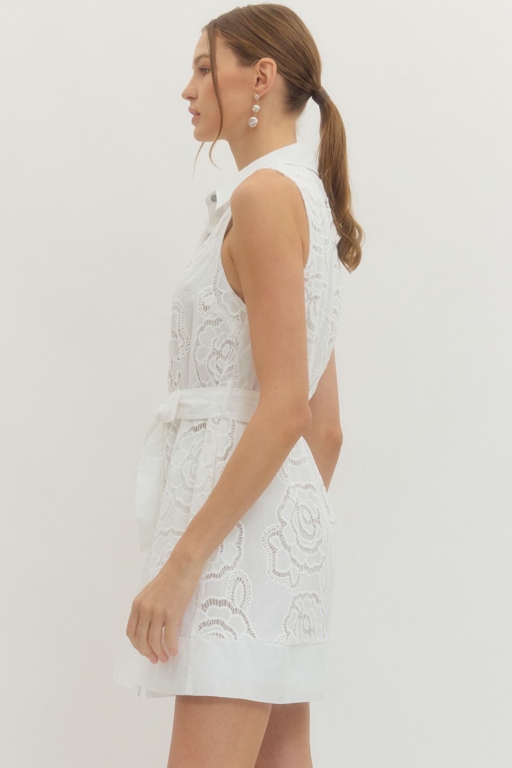 Solid sleeveless mini dress featuring floral lace overlay and self-tie belt at waist